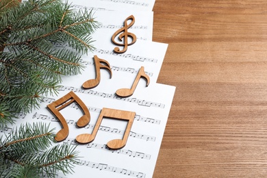 Photo of Composition with music sheets and notes on wooden background. Christmas songs concept