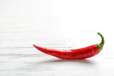 Photo of Fresh red chili pepper on wooden table. Space for text