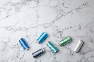 Photo of Flat lay composition with color sewing threads on marble background