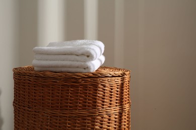 Photo of Soft towels on wicker basket indoors, space for text