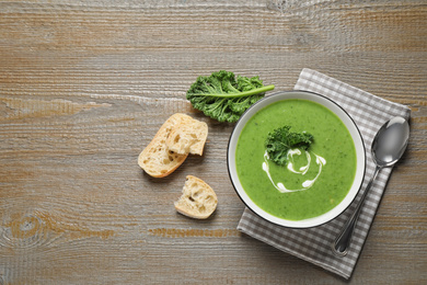 Tasty kale soup served on wooden table, flat lay