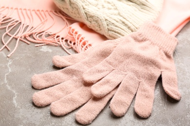 Photo of Stylish pink gloves, scarf and hat on light grey marble table, closeup