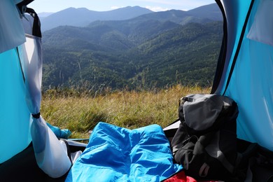 Camping tent with sleeping bag in mountains, view from inside