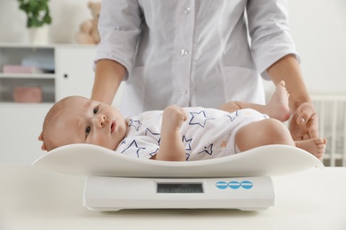 Photo of Doctor weighting baby on scales in light room