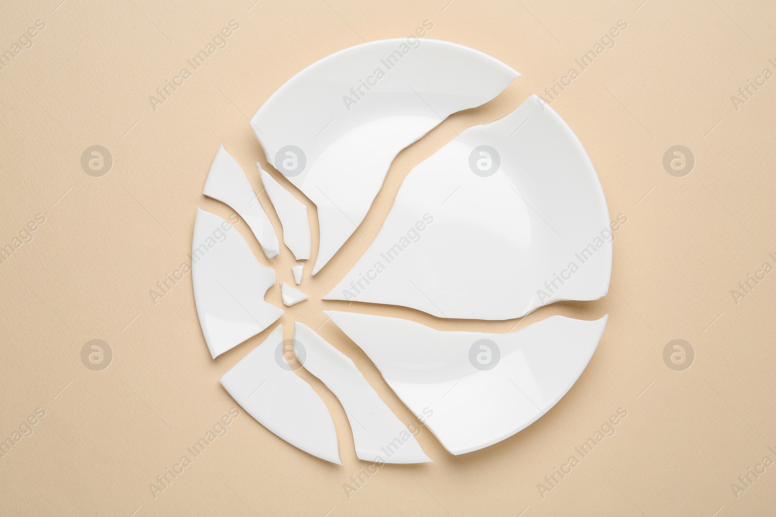 Photo of Pieces of broken ceramic plate on beige background, flat lay