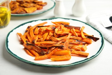 Plate with baked sweet potato slices on table, closeup