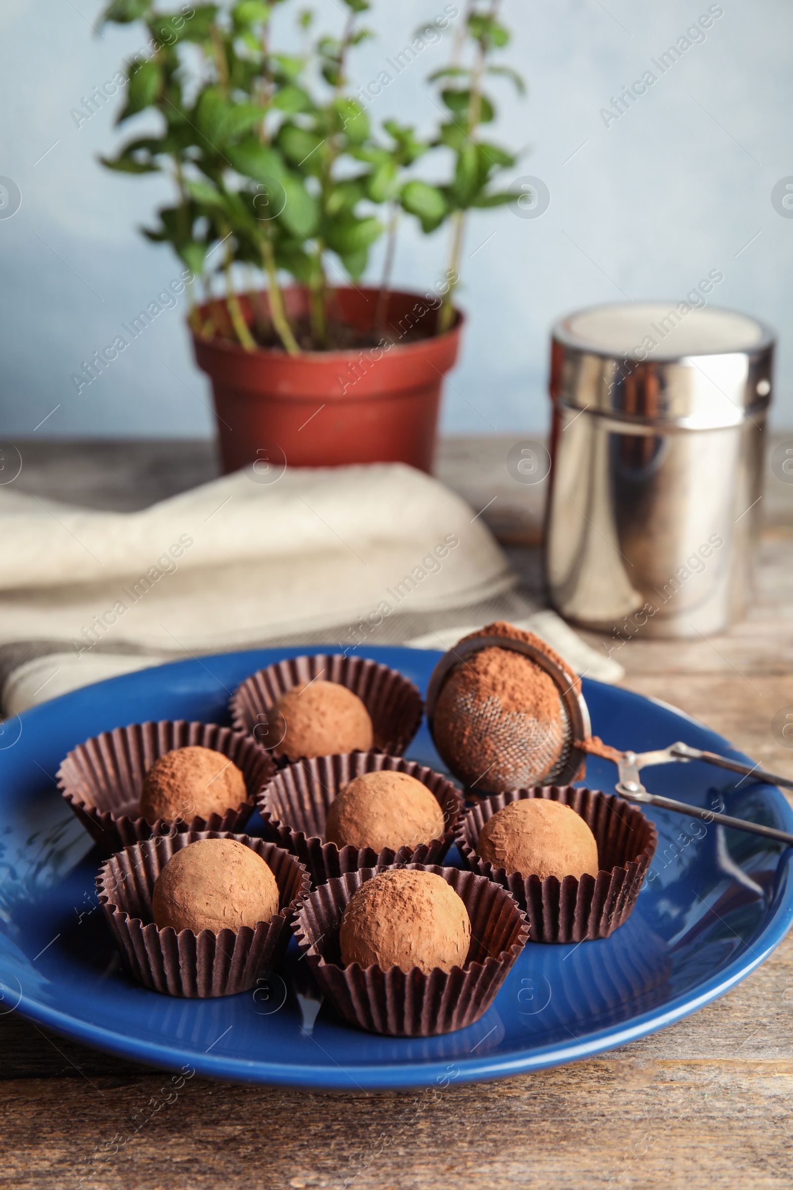 Photo of Plate with chocolate truffles on wooden table