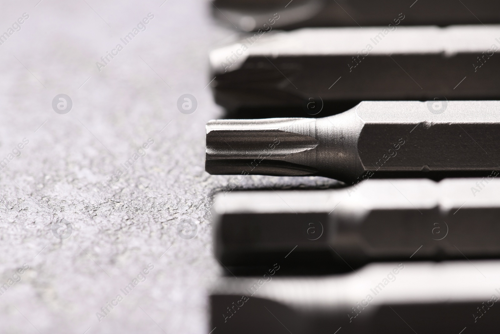 Photo of Different screwdriver bits on grey table, closeup
