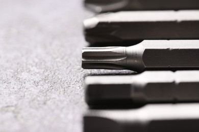 Different screwdriver bits on grey table, closeup