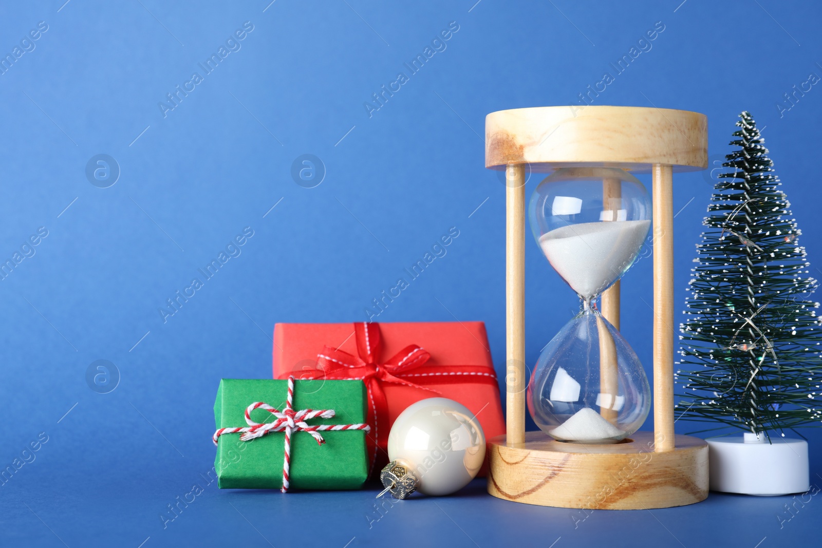 Photo of Festive composition with hourglass on blue background. Christmas countdown