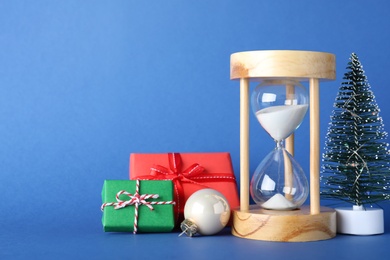 Photo of Festive composition with hourglass on blue background. Christmas countdown