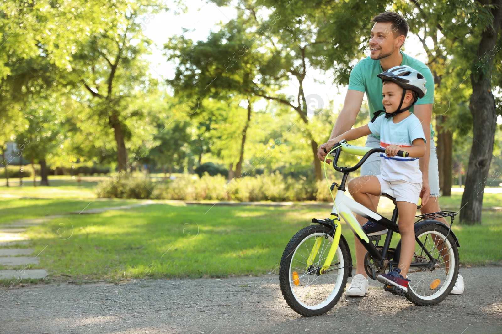 Photo of Happy father teaching his son to ride bicycle in park