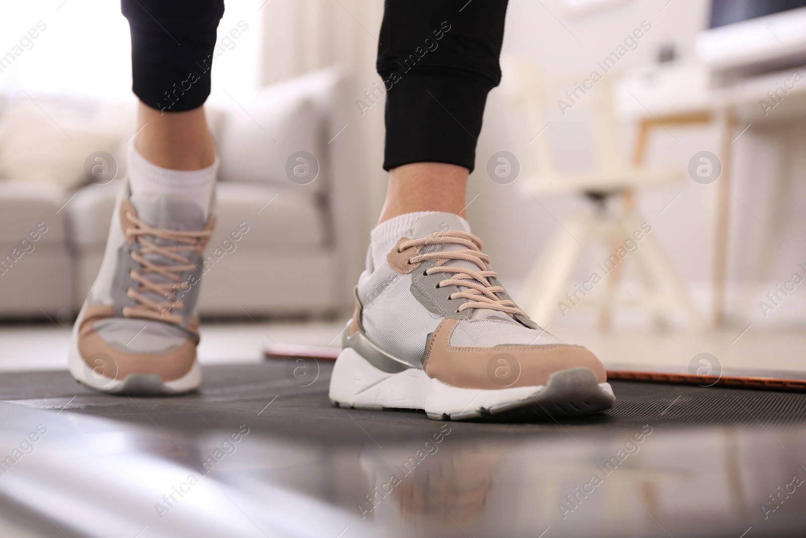 Photo of Woman training on walking treadmill at home, closeup