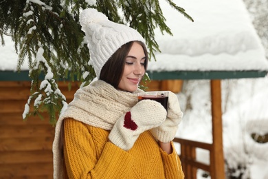 Happy beautiful woman with mulled wine outdoors on snowy day 