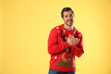 Photo of Portrait of happy young man in Christmas sweater on yellow background