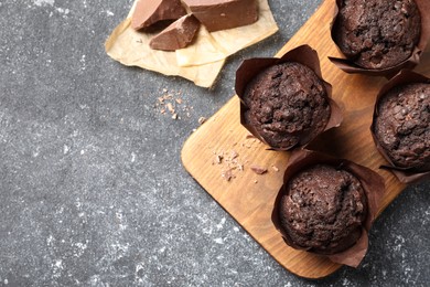 Photo of Tasty chocolate muffins on grey table, top view. Space for text