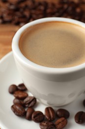 Photo of Cup of hot aromatic coffee and roasted beans on table, closeup