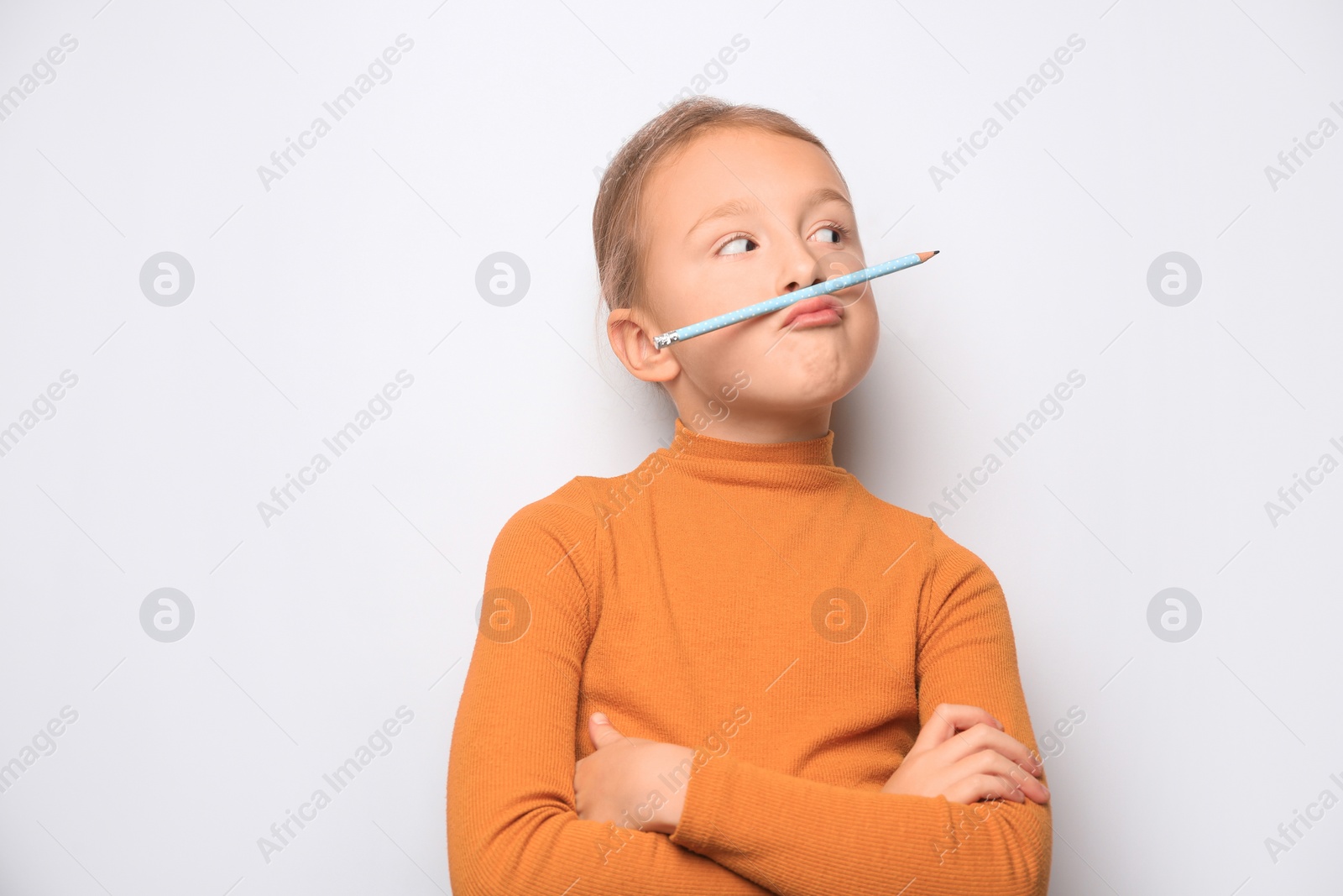 Photo of Funny little girl with pencil on white background. Space for text