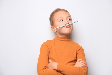 Photo of Funny little girl with pencil on white background. Space for text