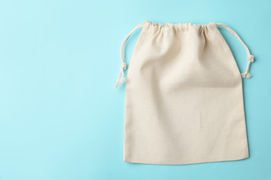 Photo of Cotton eco bag on light blue background, top view. Space for text