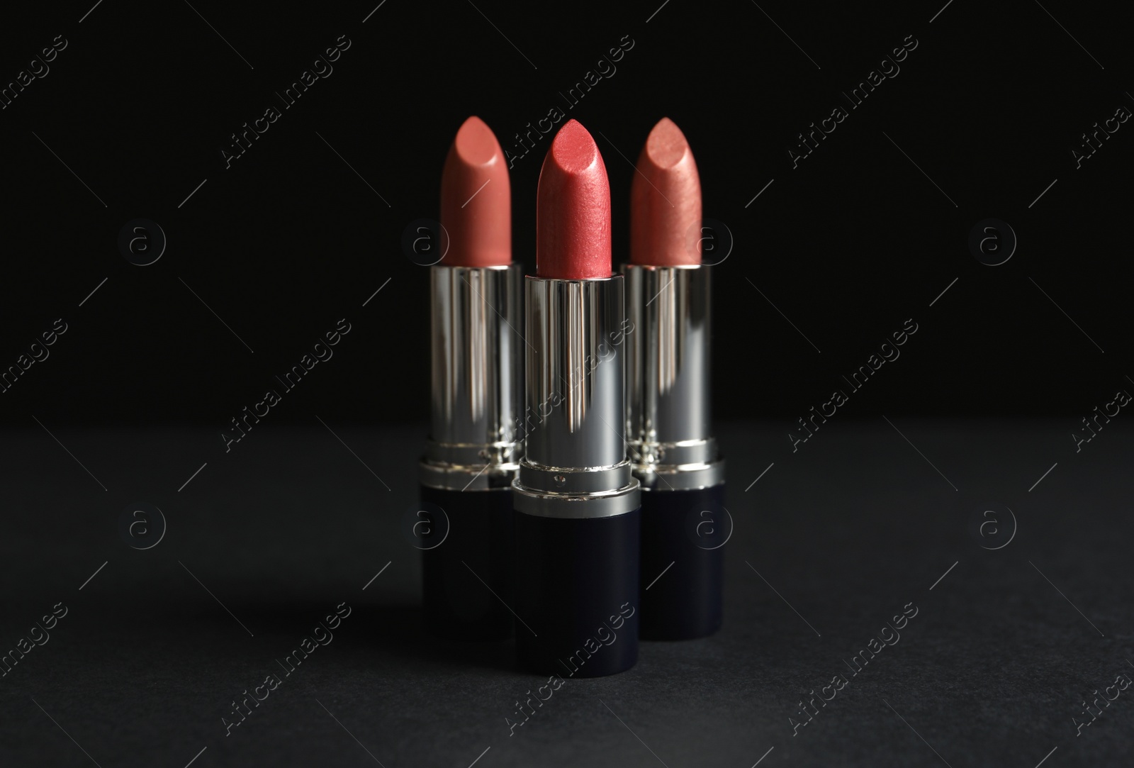 Photo of Different lipsticks on table against dark background