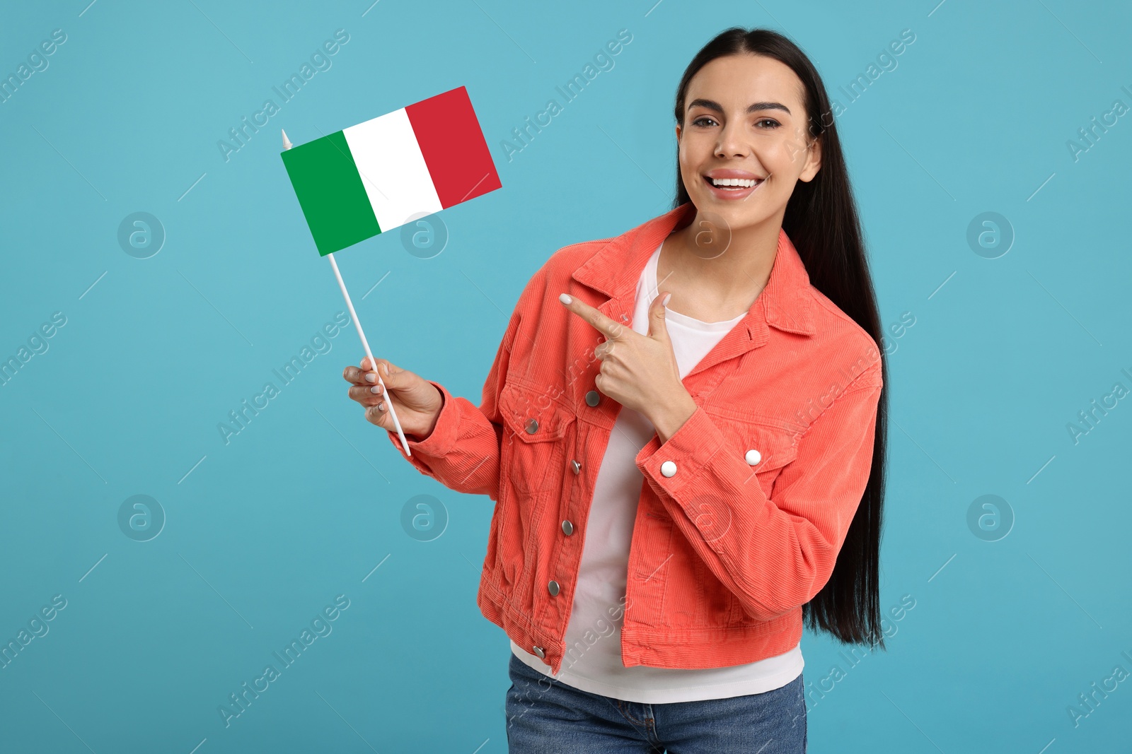 Image of Happy young woman pointing at flag of Italy on light blue background