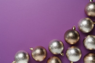 Photo of Many shiny Christmas balls on purple background, flat lay with space for text
