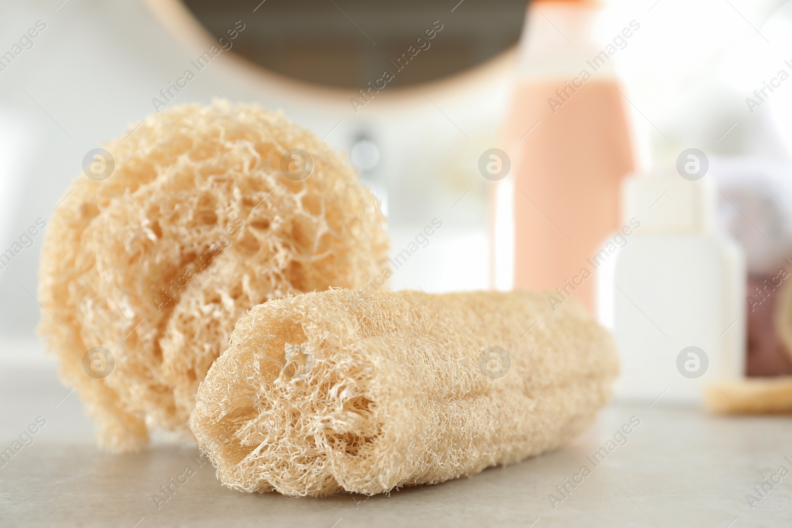 Photo of Natural loofah sponges on table in bathroom, closeup