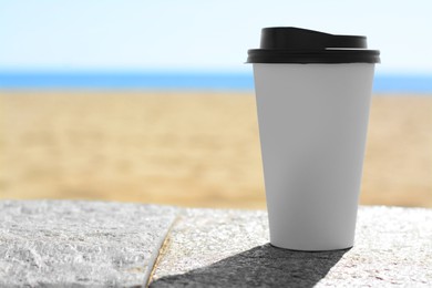 Photo of Takeaway coffee cup on stone surface outdoors. Space for text