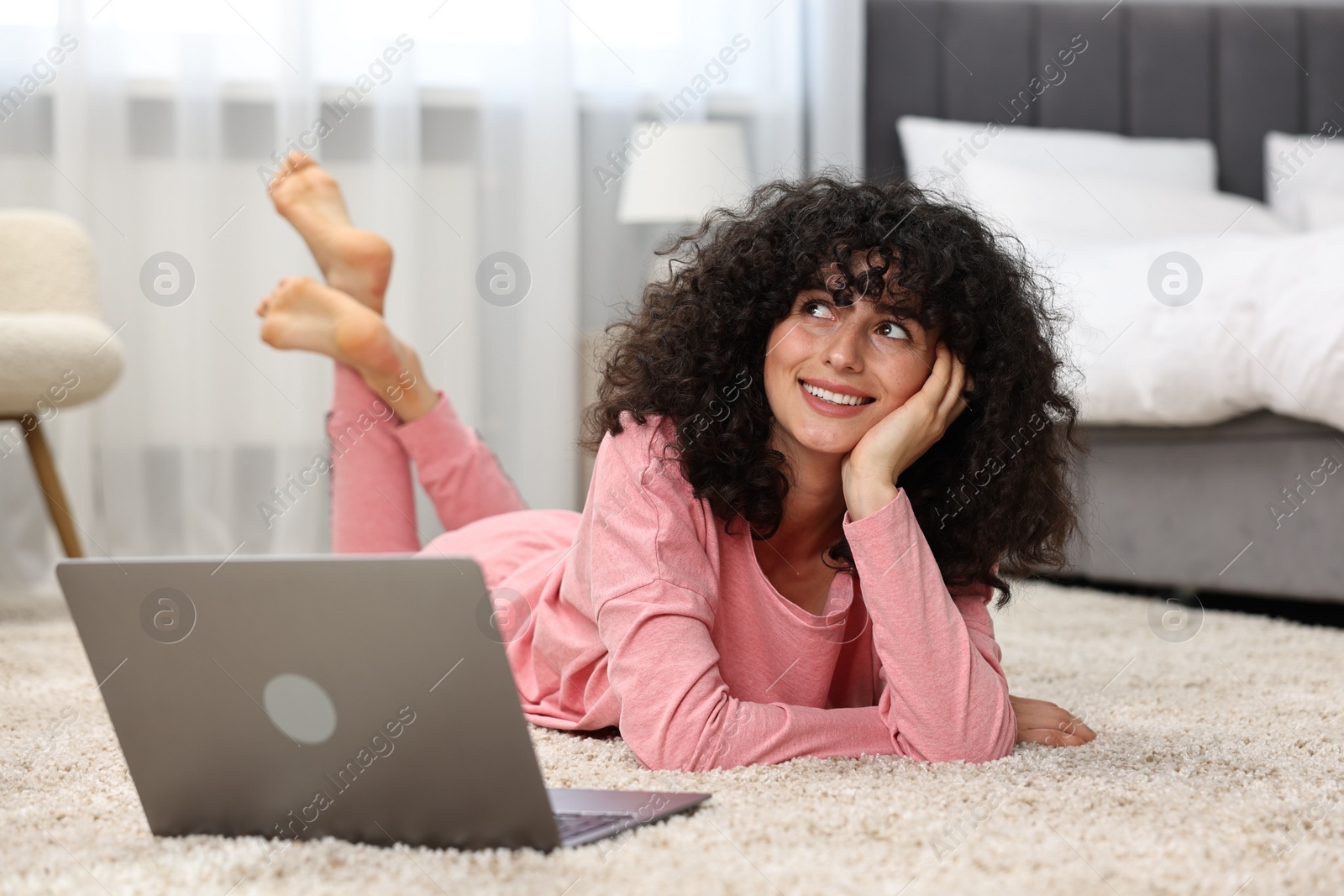 Photo of Beautiful young woman in stylish pyjama with laptop on floor at home