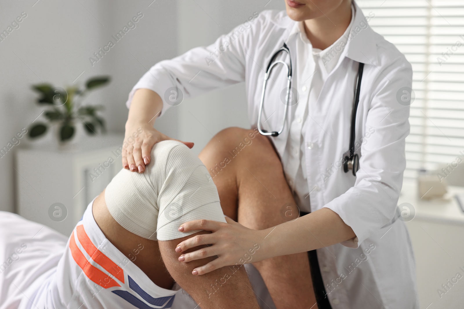 Photo of Sports injury. Doctor examining patient's knee in hospital, closeup