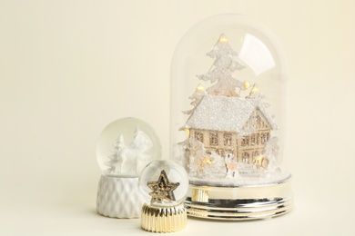 Different beautiful snow globes on beige background