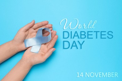 Image of World Diabetes Day. Woman holding light blue awareness ribbon on color background, top view