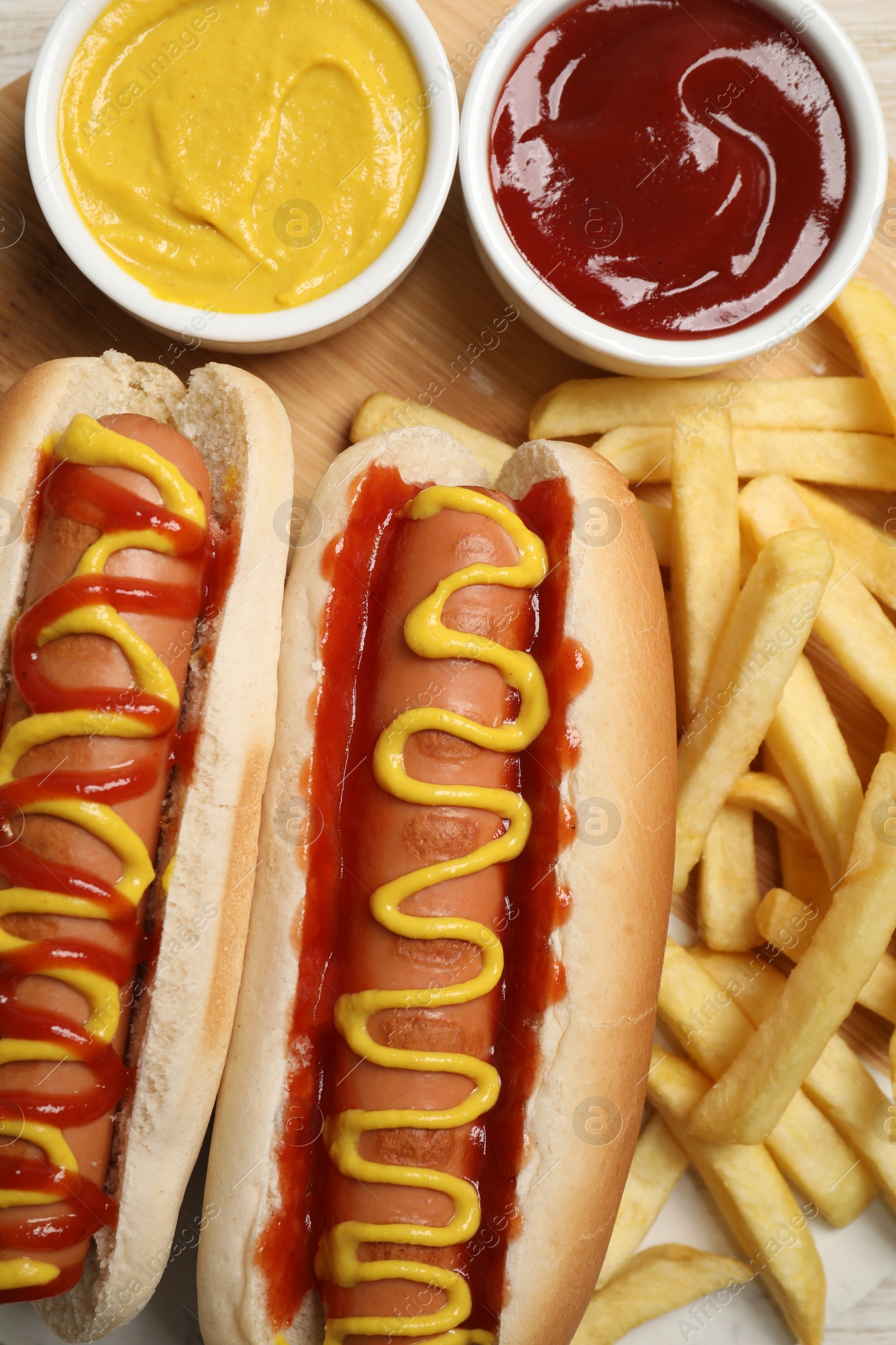 Photo of Delicious hot dogs with mustard, ketchup and potato fries on table, flat lay