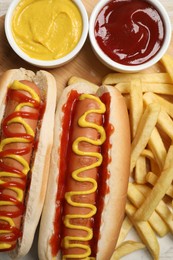Photo of Delicious hot dogs with mustard, ketchup and potato fries on table, flat lay