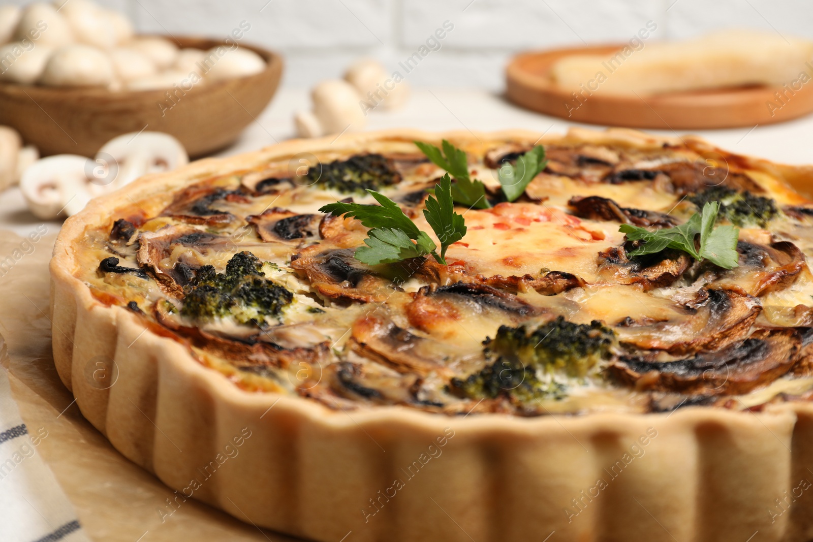 Photo of Delicious quiche with mushrooms and parsley on parchment paper, closeup