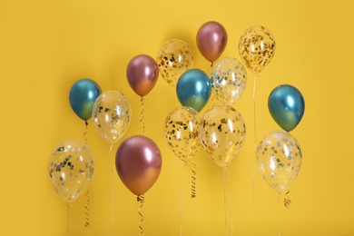 Bright balloons with ribbons on color background