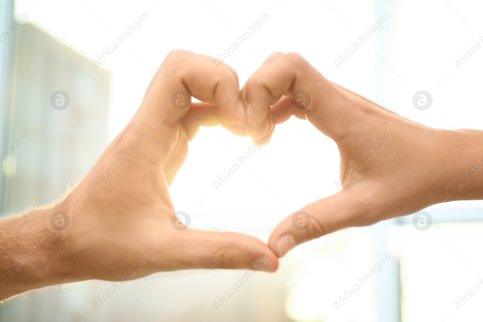 Photo of Young people forming heart with hands indoors, closeup. Happy family