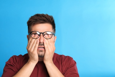 Photo of Young man with glasses covering eyes on blue background