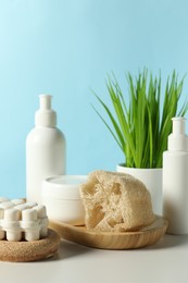 Photo of Different bath accessories and houseplant on white table against light blue background