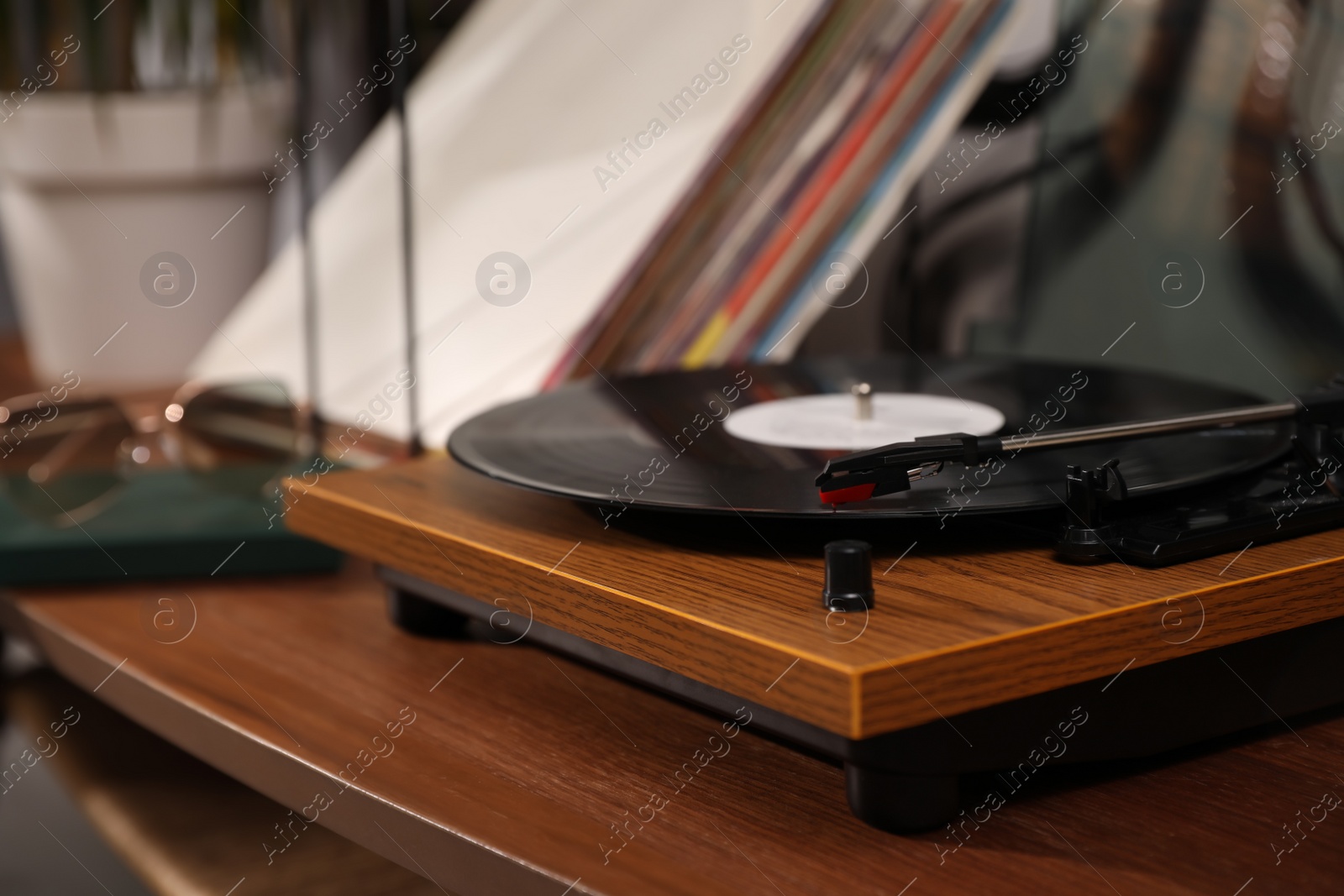 Photo of Stylish turntable with vinyl disc on table in room, closeup