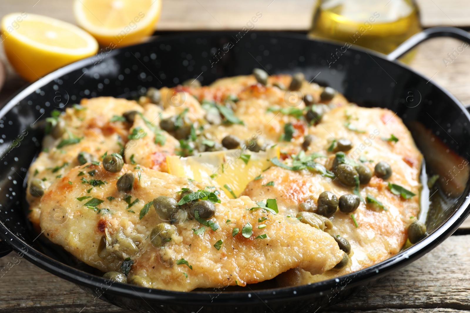 Photo of Delicious chicken piccata with herbs on wooden table, closeup