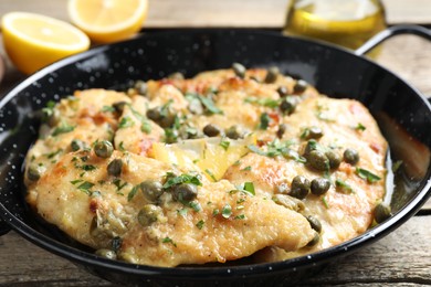 Delicious chicken piccata with herbs on wooden table, closeup