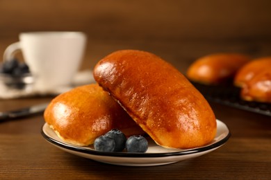Delicious baked pirozhki with blueberries on wooden table, closeup