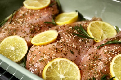 Photo of Chicken breasts with lemon and rosemary in baking dish, closeup