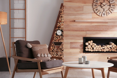 Photo of Decorative fireplace with stacked wood in cozy living room interior