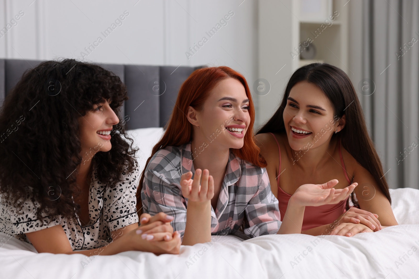Photo of Happy young friends on bed at home