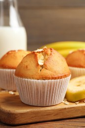 Tasty muffins served with banana on wooden table, closeup