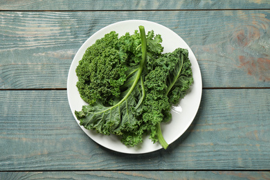 Photo of Fresh kale leaves on light blue wooden table, top view