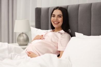 Happy pregnant woman in bed at home